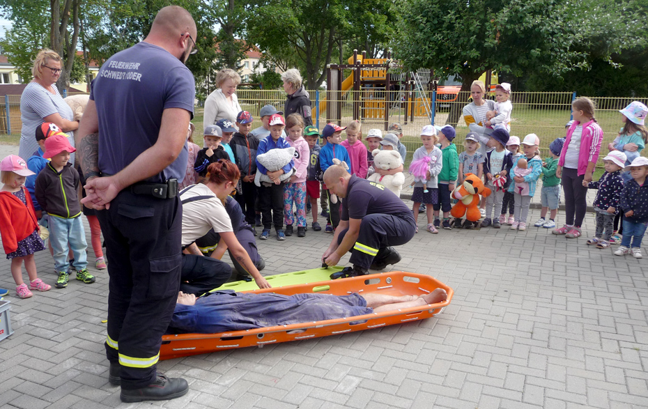 Foto: Feuerwehrleute zeigen den Kindern, wie jemand gerettet wird