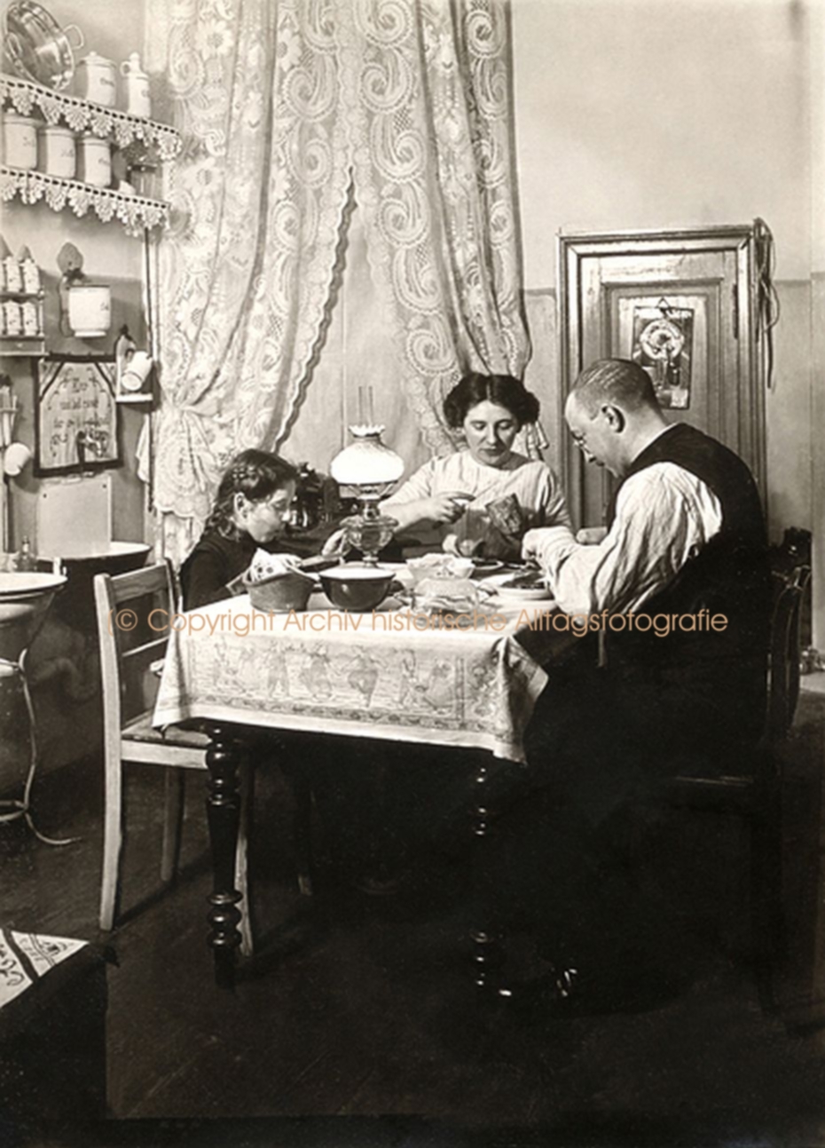 Vater, Mutter und ein Kind sitzen an einem Tisch und essen gemeinsam Abendbrot.