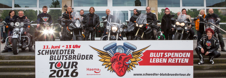 Gruppenfoto mehrerer Biker mit Werbebanner