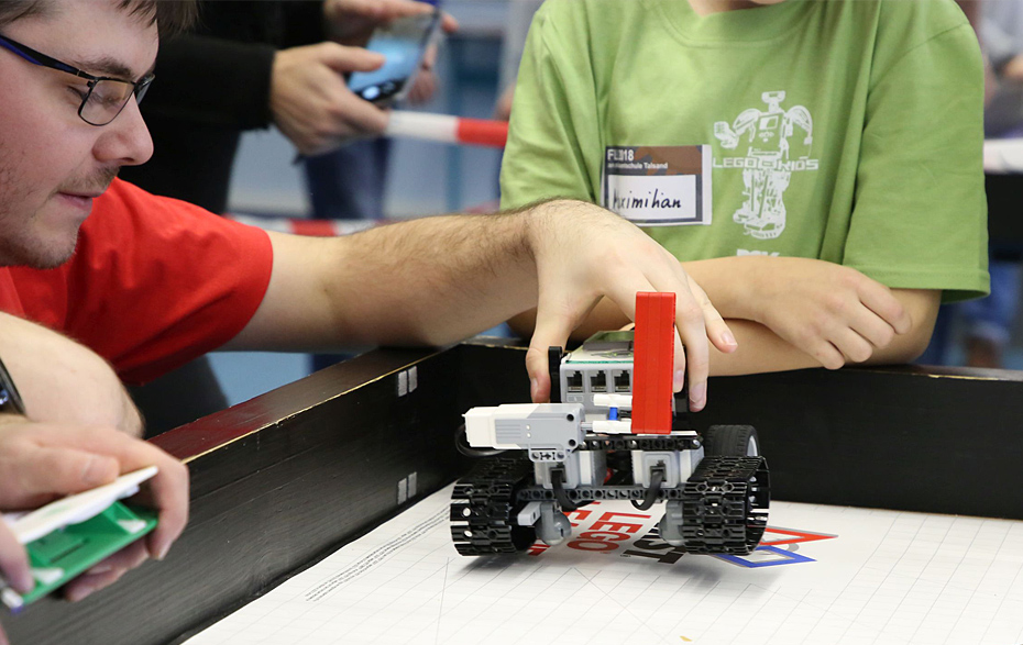 Foto: Ein Roboter aus Lego wird auf das Spiefeld gesetzt.