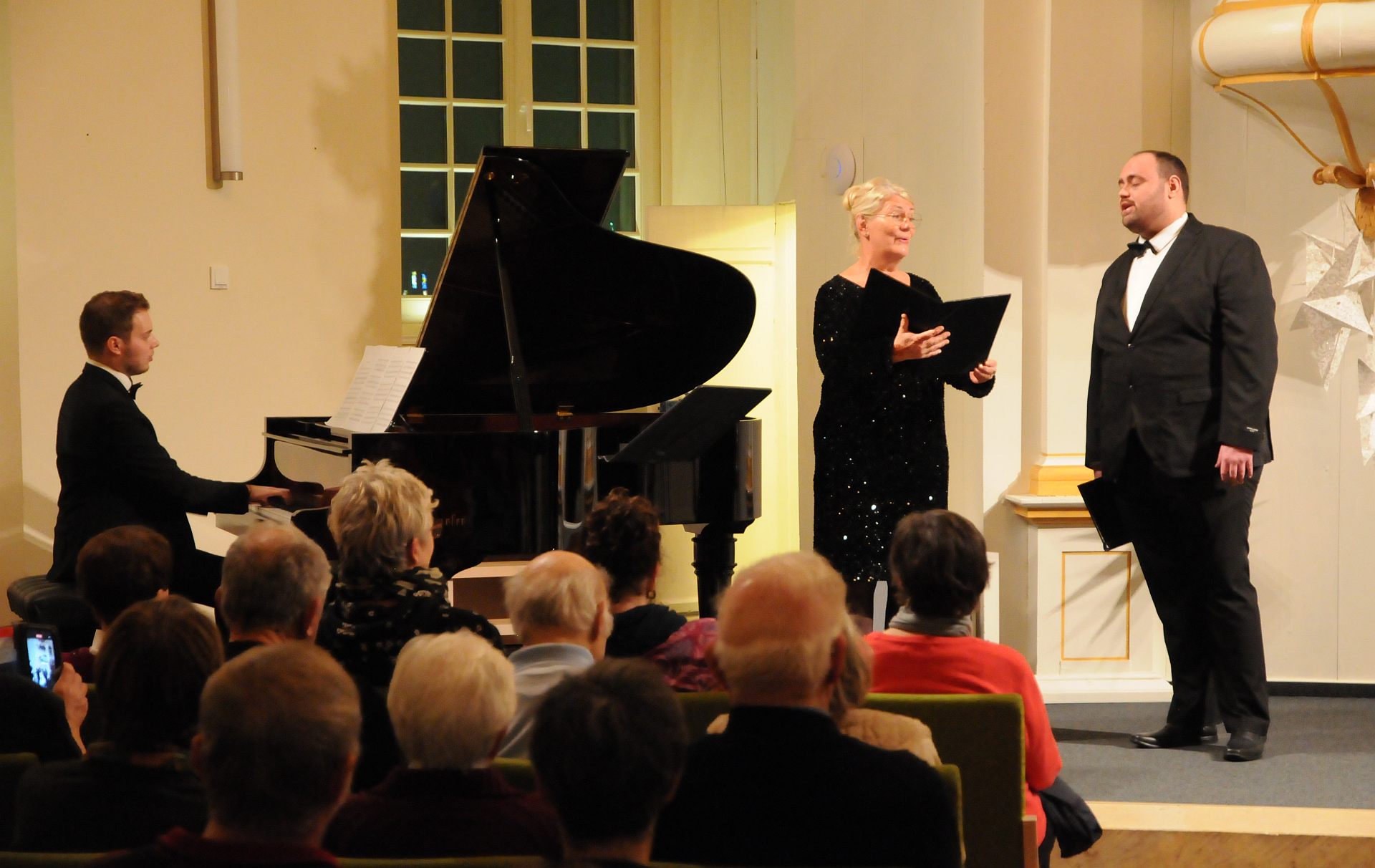 Foto: eine Sängerin, ein Sänger und ein Mann am Klavier musizieren vor Publikum im Berlischky-Pavillon