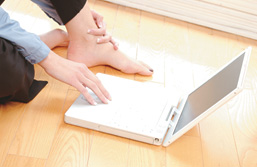 Foto: Frauenhand am Laptop, der auf dem Fußboden liegt