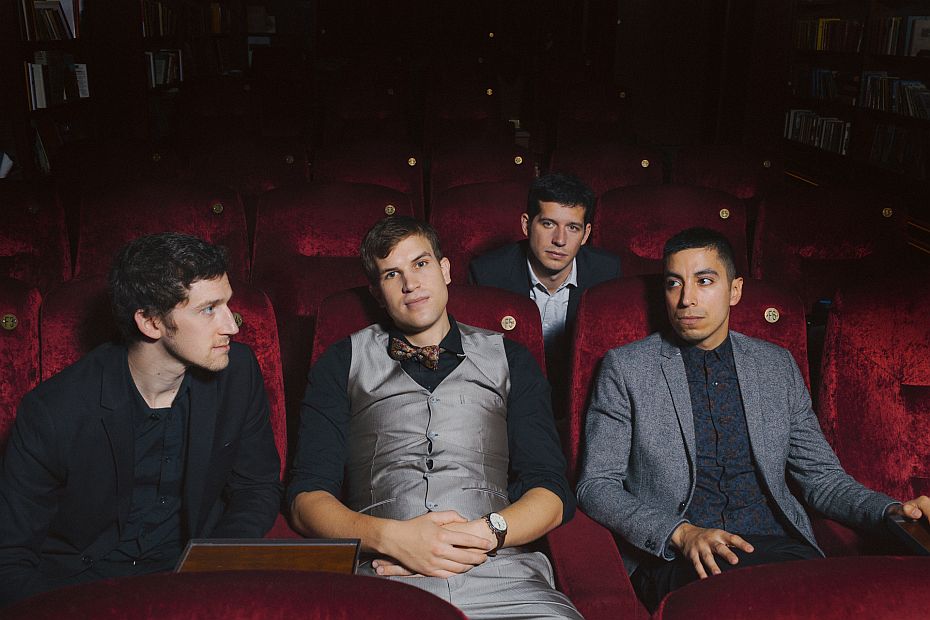 4 junge Musiker sitzen in einem Kinosaal.