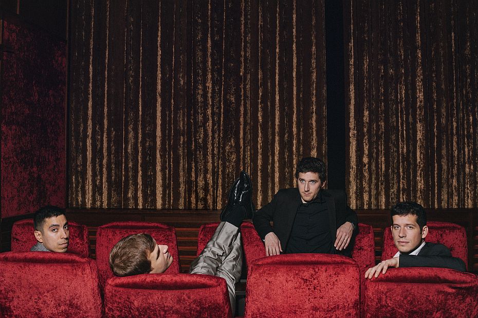 4 junge Musiker sitzen in einem Kinosaal.