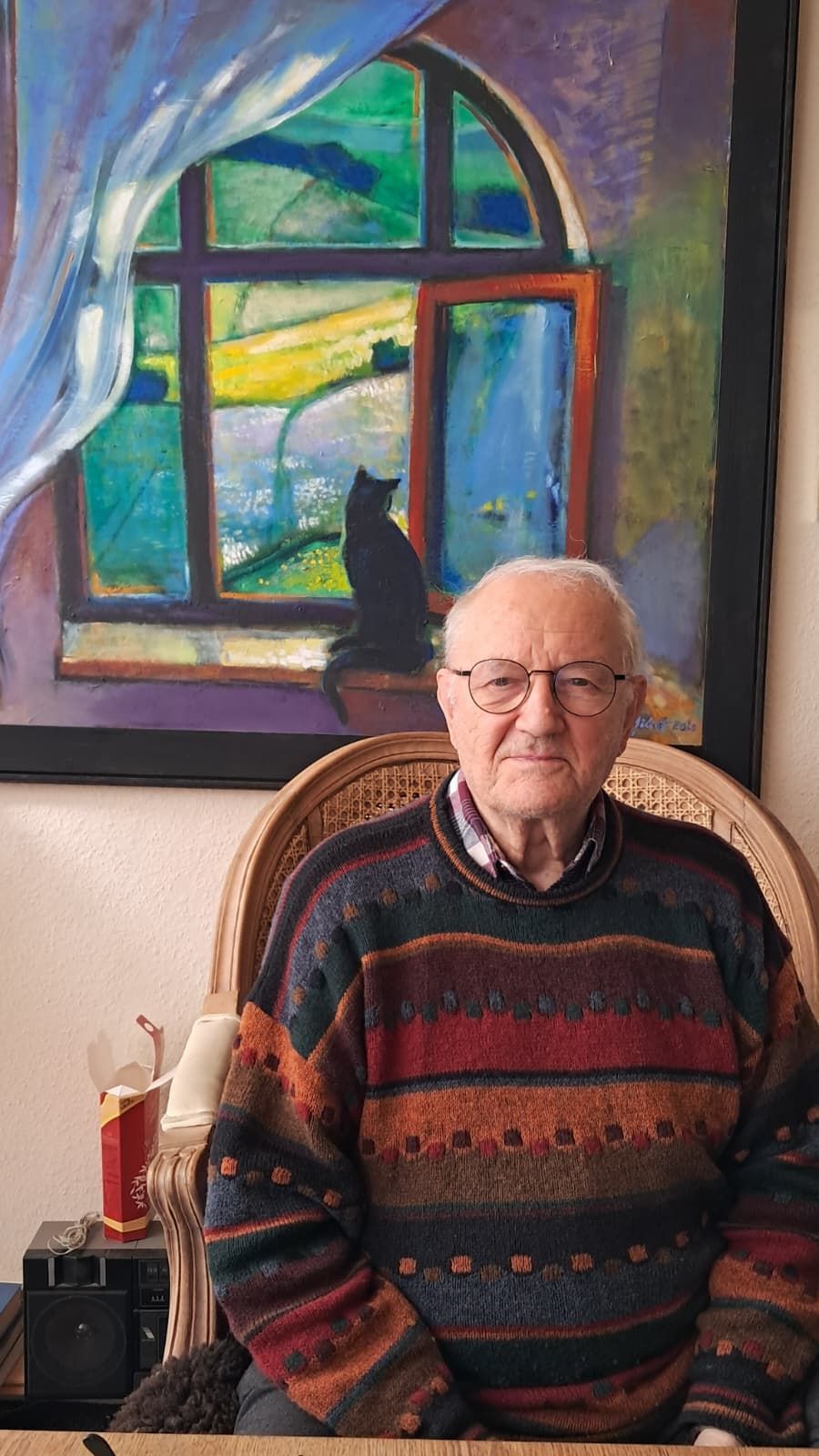 Foto: sitzender Künstler vor einem seiner Werke Foto: sitzender Künstler vor einem seiner Werke