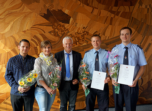 Foto: Drei Männer und eine Frau mit Blumen im Gruppenbild mit einem Mann