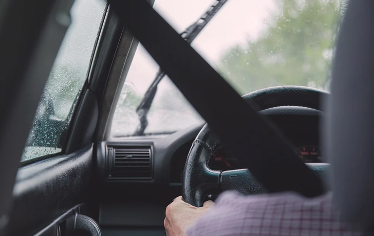 Foto: im Auto Blick auf die verregnete Frontscheibe von hinten am Fahrer vorbei