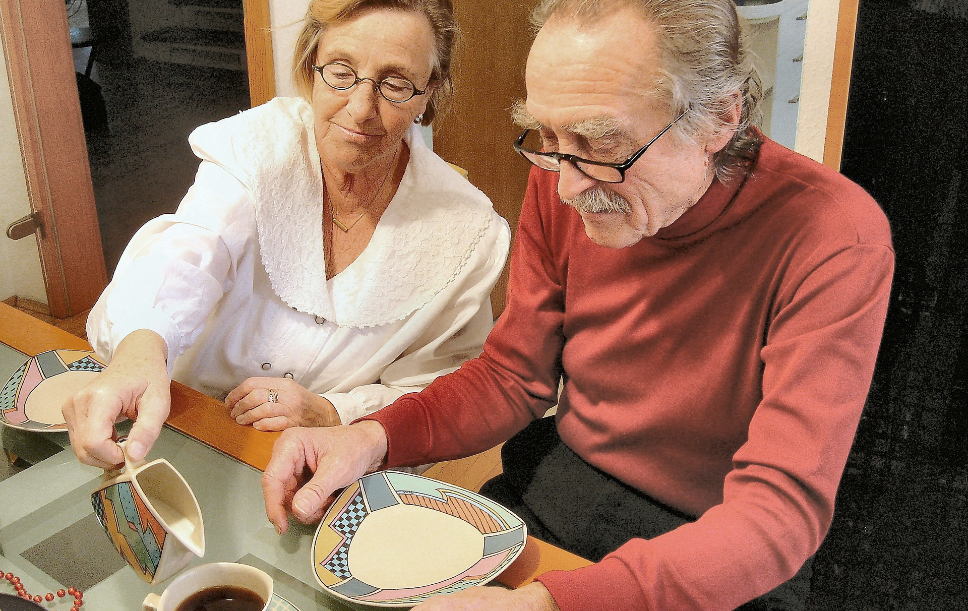 Foto: Frau gießt einem alten Mann Milch in den Kaffee