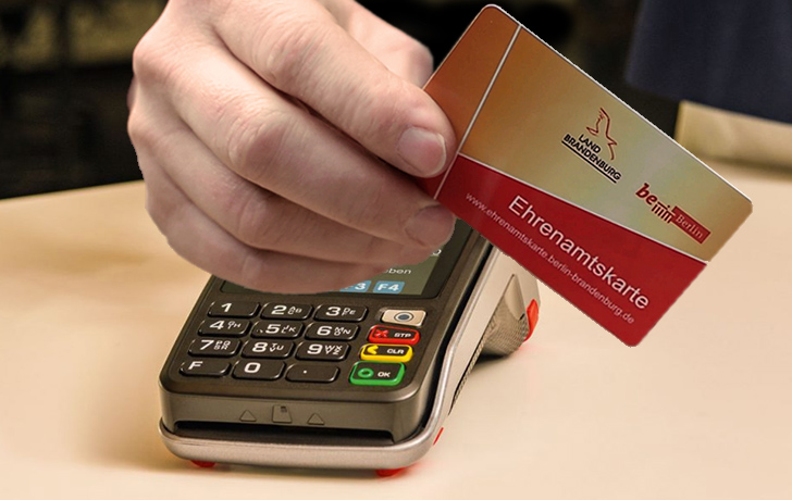 Foto: eine Hand hält die rot-goldene Karte über ein Kartenlesegerät