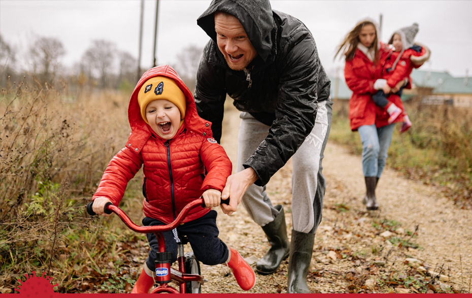 Foto: Familie beim Spaziergang, Kind auf dem Laufrad