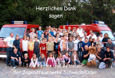 Foto: Gruppenfoto von Kindern und Betreuern der Jugendfeuerwehr mit 2 Löschfahrzeugen