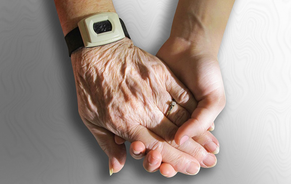 Foto: junge Hand hält ältere Hand mit Notrufknopf