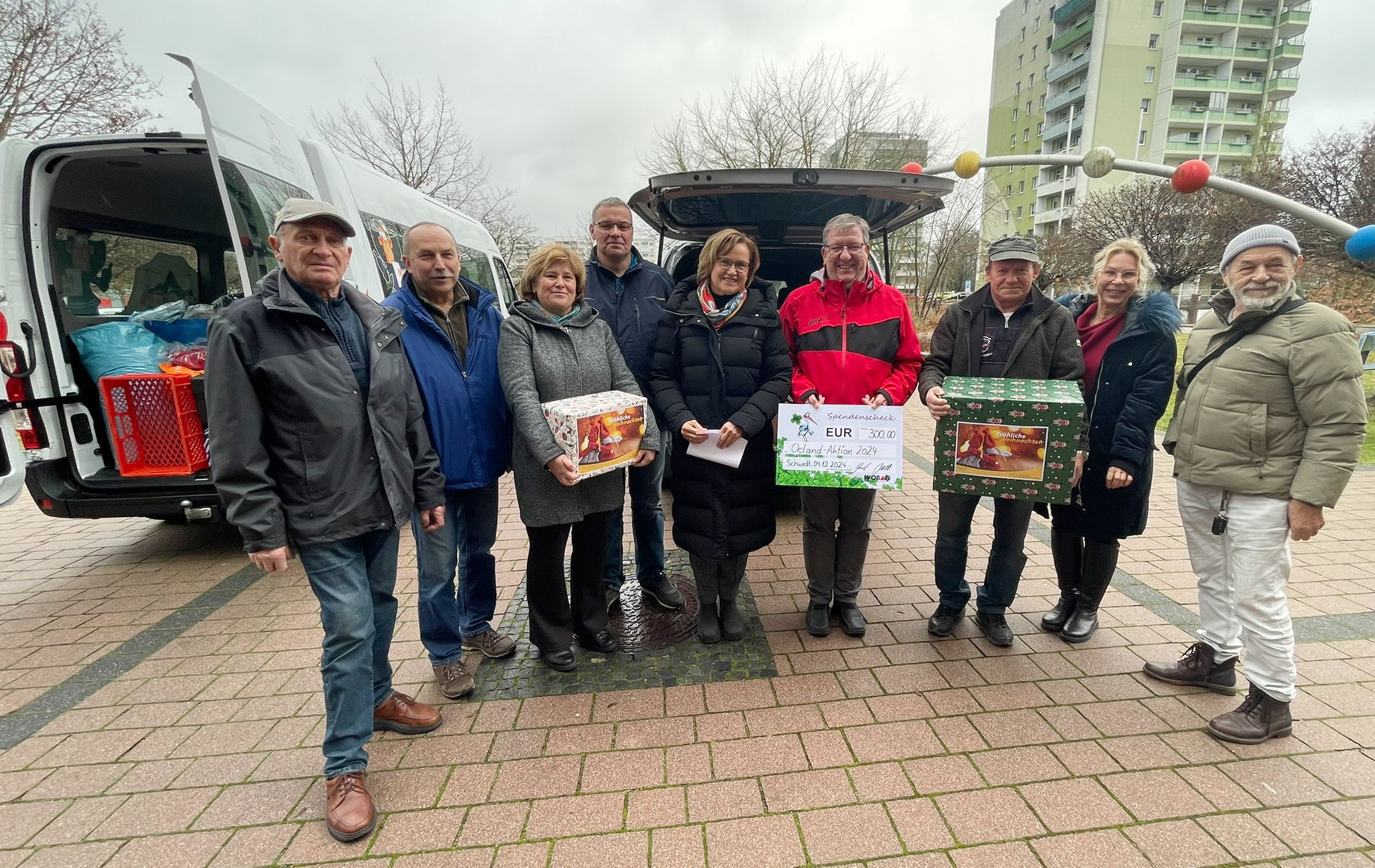 Gruppenfoto vor den Wagen voller Weihnachtspäckchen