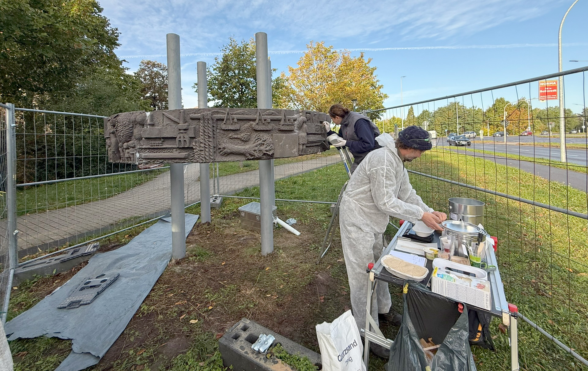 Foto: zwei Personen an und vor der Stele
