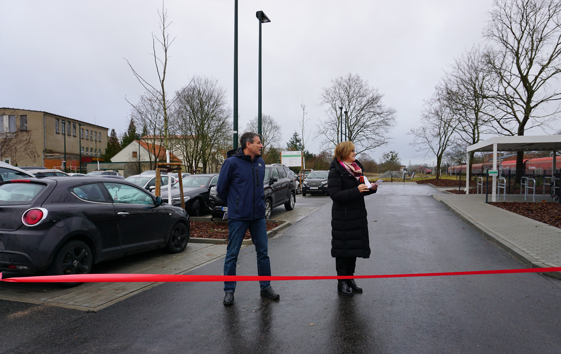 Foto: 2 Personen hinter dem roten Band auf dem Parkplatz