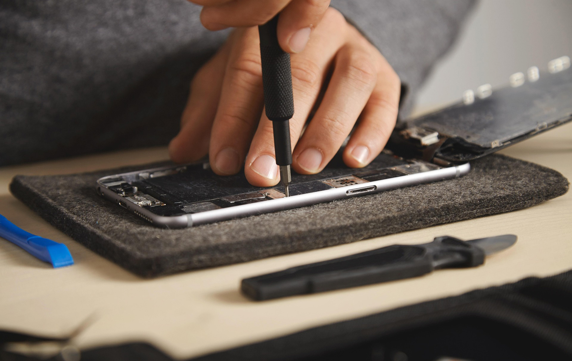 Foto: Hand mit Schraubendreher im Innern eines Smartphones