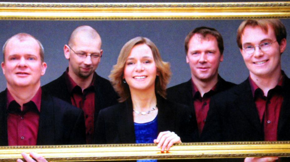 Fünf Musiker – vier Männer und eine Frau – schauen durch einen Bilderrahmen