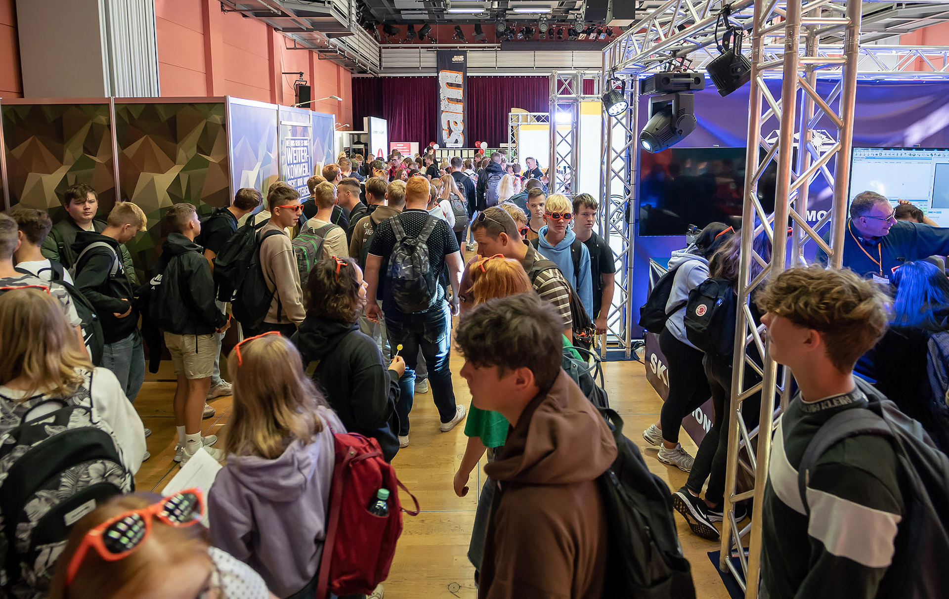 Foto: viele junge Leute gehen von Messestand zu Messestand