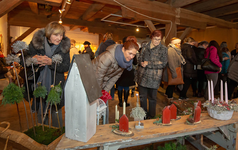 Foto: Frauen betrachten die ausgestellten weihnachtlichen Dekoartikel in der Galerie