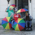 Foto: Wasserdusche auf 4 Personen, 2 im Rollstuhl und 4 bunte DGM-Schirme