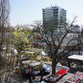 Foto vom 15. April 2015: Blick von oben auf Marktstände, grünende Bäume, Kompaktbau und Hochhaus