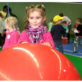 Foto: Kita-Mädchen lächelt beim Halten einen Gymnastikballs in die Kamera.