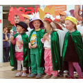 Foto: Kindergruppe mit grünen Umhängen und verschieden Kopfschmuck singen Lieder.