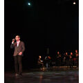Foto: Ein Mann singt am Bühnenrand mit der Big Band.