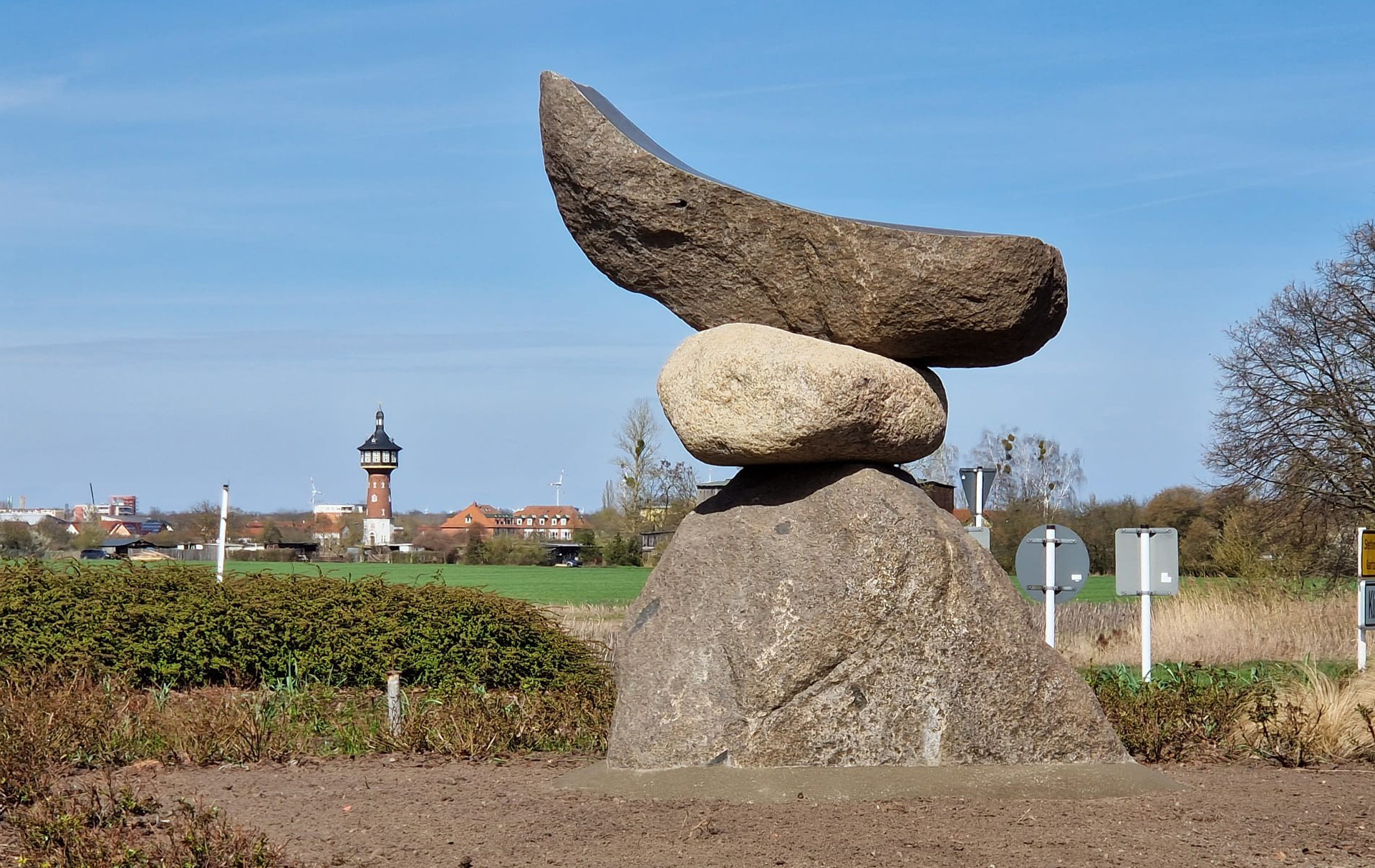 Foto: Feldsteinskulptur, im Hintergrund der Wasserturm